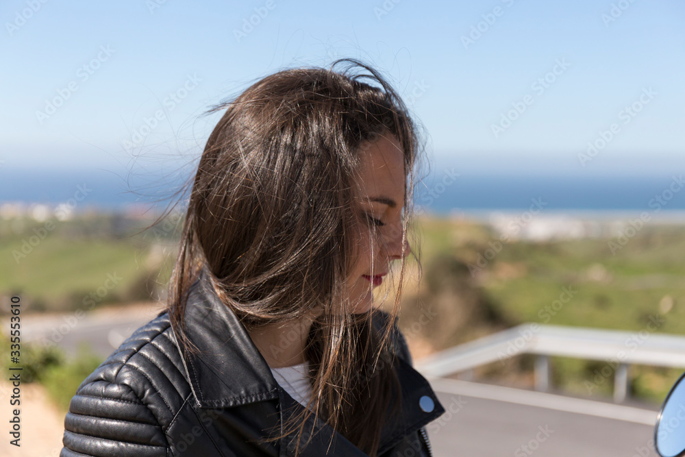 dark-haired woman in windblown black leather jacket dark-haired woman in windblown black leather jacket