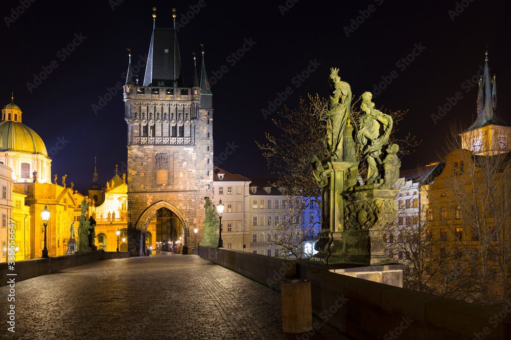 Night colorful Prague Old Town with Bridge Tower and St. Francis of Assisi Cathedral from Charles Bridge with its baroque Statues without People at the time of Coronavirus, Czech republic
