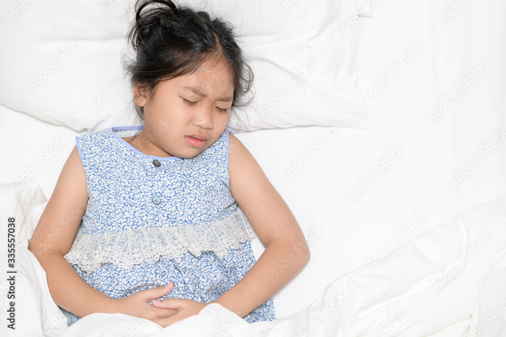 asian child suffering from stomachache and lying on bed. asian child suffering from stomachache and lying on bed.