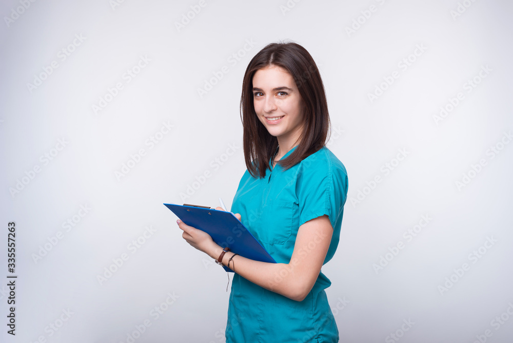 Photo of a young female doctor or dentist student is writing something on a blue paper board. Photo of a young female doctor or dentist student is writing something on a blue paper board.