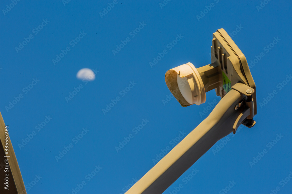 Fototapeta premium Satellite Dish with Moon in the Background Close Up and Clear Blue Sky