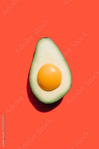 egg yolk in ripe avocado on a red background. 