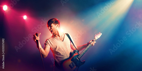Young male singer performing on a stage and playing the guitar
