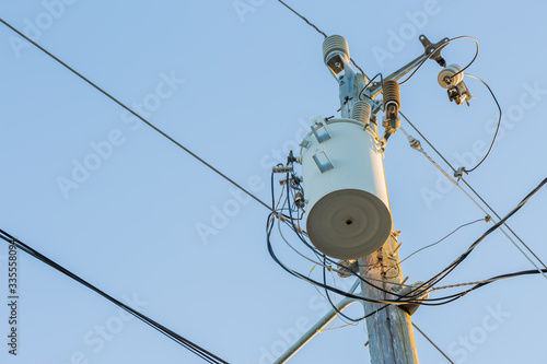 Power pole with transformer and power lines. Blue sky in the background. 
