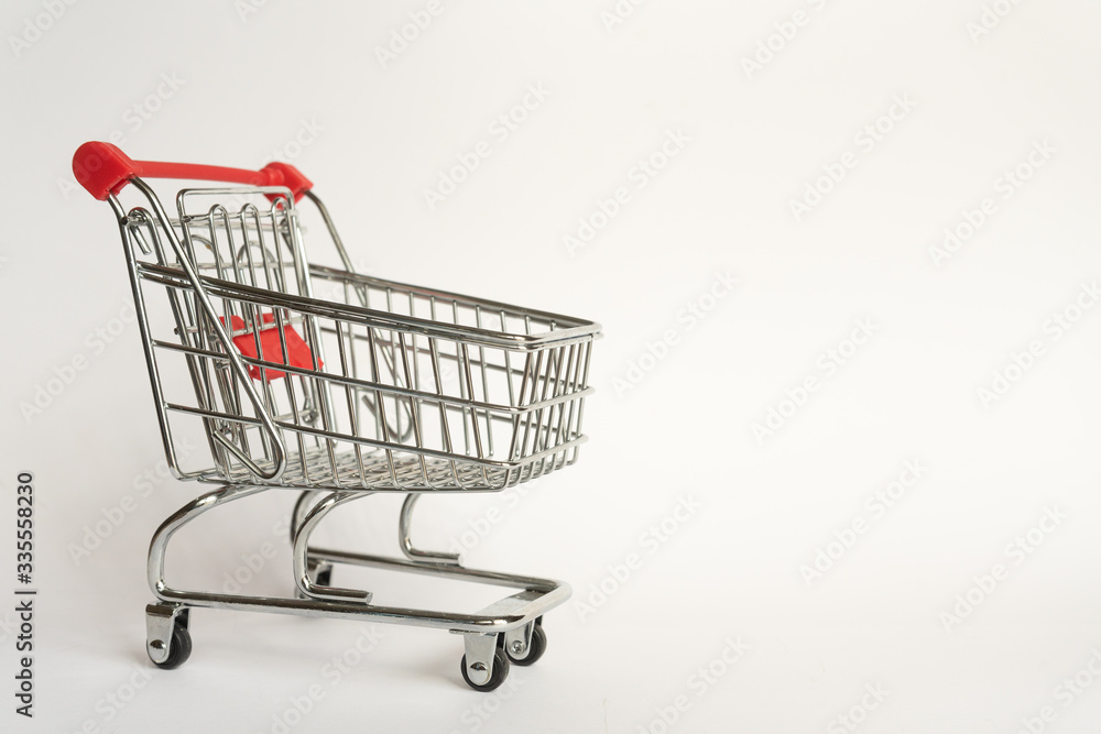 Empty supermarket consumer food trolley from steel with red plastic handle on a gray background with empty space