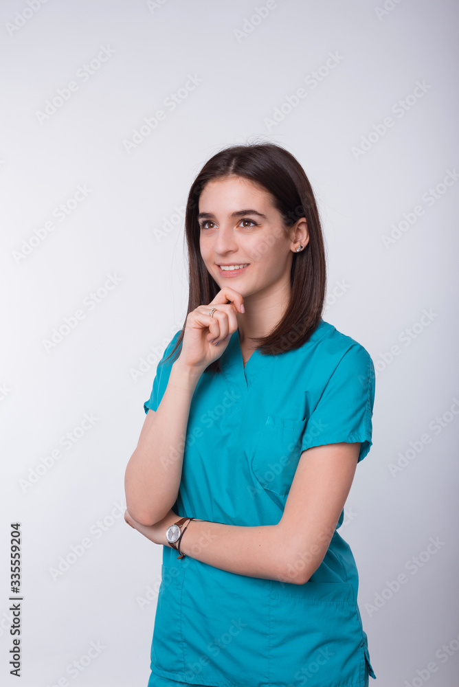 Photo of young smiling female doctor is making thinking gesture on white background. Photo of young smiling female doctor is making thinking gesture on white background.