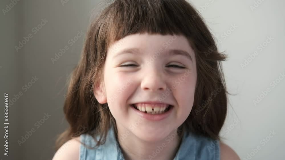 A 6-7 year old girl looks at the camera and laughs. Close up. A 6-7 year old girl looks at the camera and laughs. Close up.