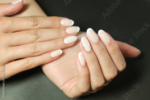 Fashionable gentle manicure gel Polish on natural nails with a white monogram pattern on the hands of a modern girl