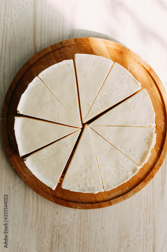  Cake cut into slices on a short dough. Cream cheesecake on a wooden Board.