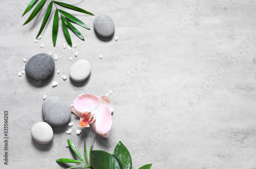 Spa concept on stone background, palm leaves, flower, zen, grey stones, top view, copy space.