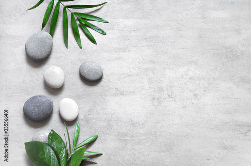 Grey spa background, spa concept, palm leaves and grey stones.