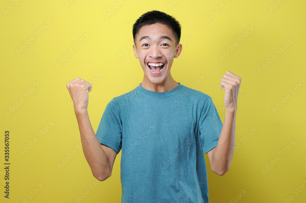 Portrait of happy young Asian man excited raising both his hands Portrait of happy young Asian man excited raising both his hands