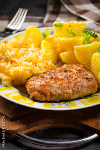 Minced pork cutlet served with potatoes and sauerkraut salad. photo