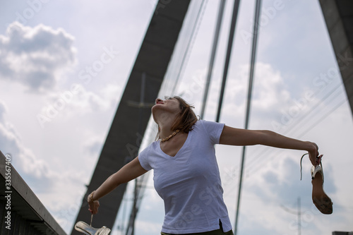 horizontal photo of a happy young girl in a white t-shirt and green skirt on a background of a bridge