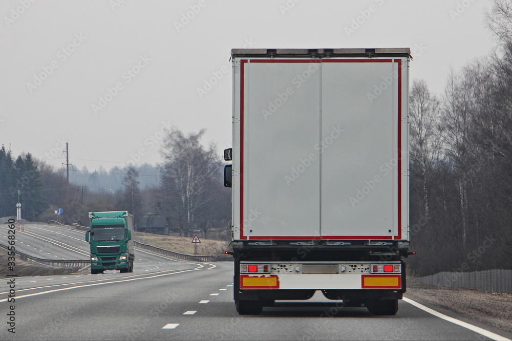 Trucks with on highway road at spring day, transportation logistics