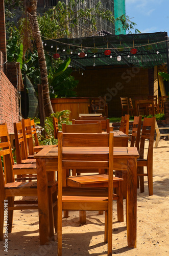 Wooden tables and chairs on the beach. Outdoor cafe. No people