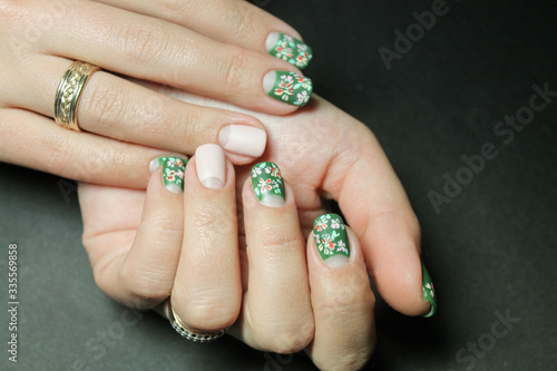 Beautiful moon manicure gel Polish on natural nails with flower design gel Polish drawn by hand on the hands of a young woman