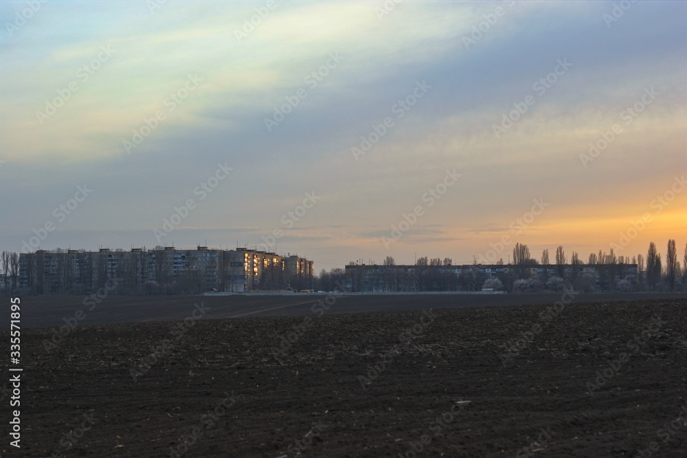 Obraz premium The beginning of urban development behind a plowed field in spring
