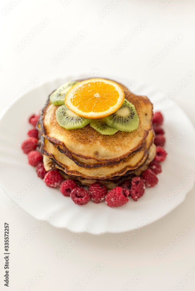 Top view of pancakes with orange, kiwi and raspberries.