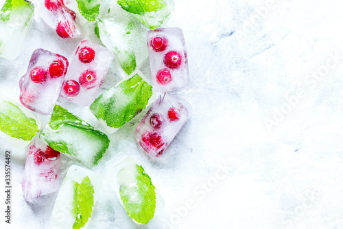 mint and red berries in ice cubes stone background top view mockup