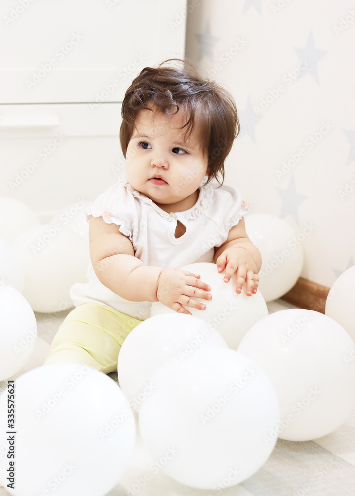 cute baby playing with white inflatable helium balloons