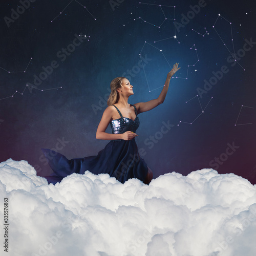 Romantic young woman in a blue dress against a blue sky aspires to the stars.