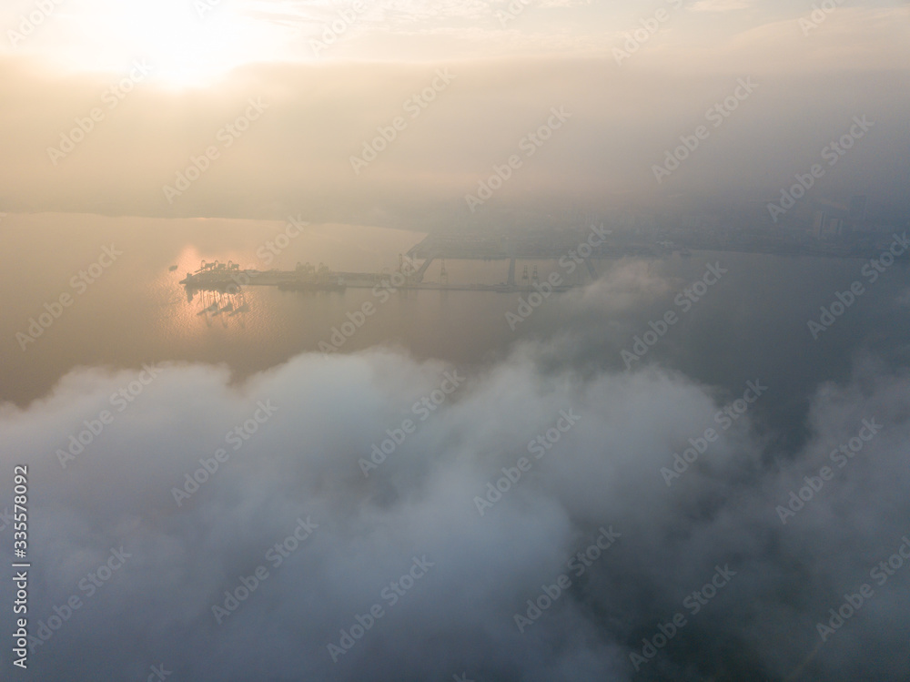 Aerial view Container Terminal in early morning over sea cloud.