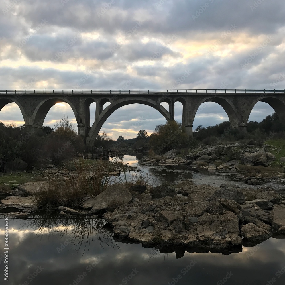 Fototapeta premium Roman bridge over ardila river with sunset in Oliva de la Frontera, Spain
