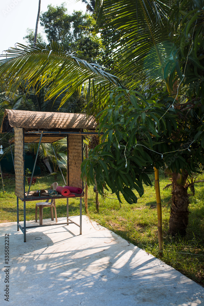 Wicker gazebo among tropical palms with yoga mats. A place for outdoor