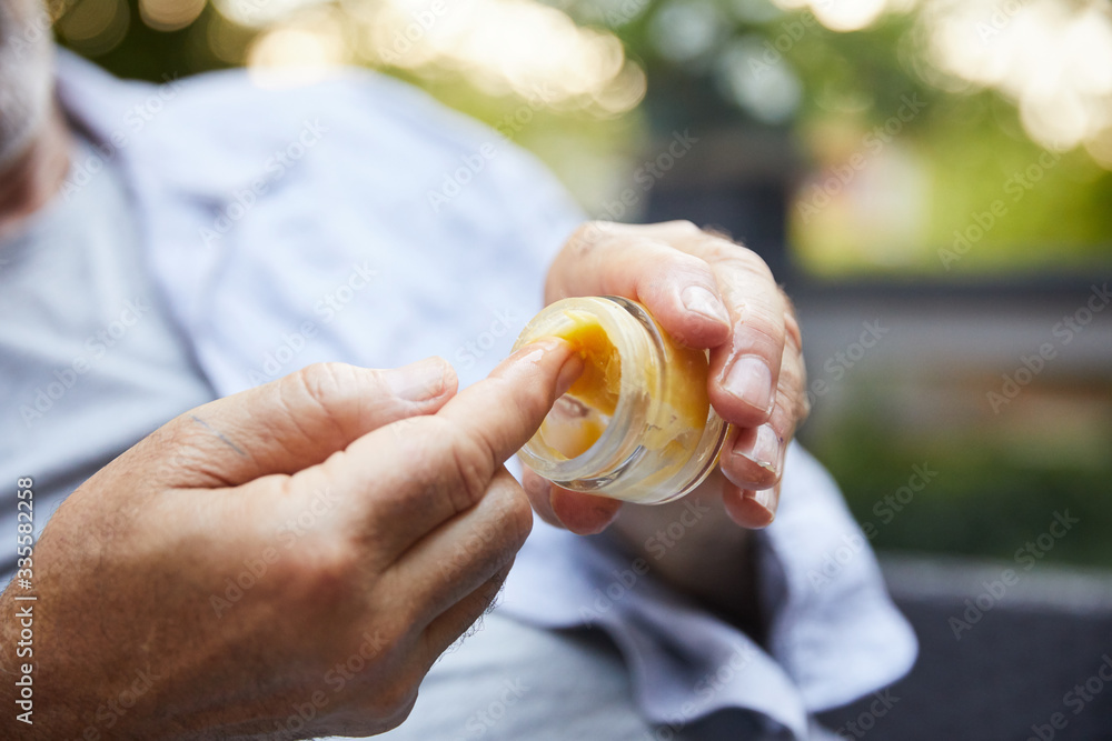 Older man dipping his finger into a jar of CBD oil