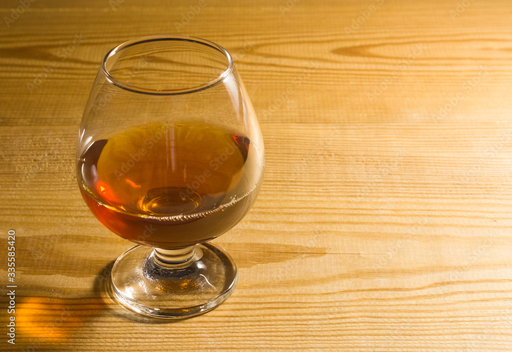 Glass glass with cognac on a wooden table. Free space for text on the side. Glass glass with cognac on a wooden table. Free space for text on the side.