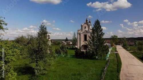 Renewed ancient Christian Orthodox Church on green yard near dirt road in traditional Ukrainian village. Village landscape. Aerial drone 4k, zoom in photo