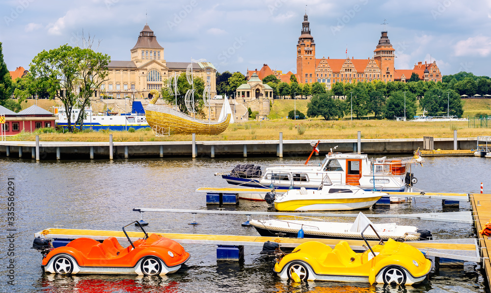 Pedalos and boats docked on Rampart of Brave embankment of Odra River. National Museum, Regional Authority and Passport Office in background, Szczecin - obrazy, fototapety, plakaty 