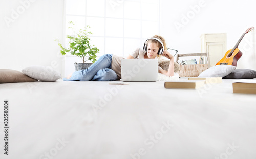 young woman sitting in living room studying music with headphones and computer, stay at home concept