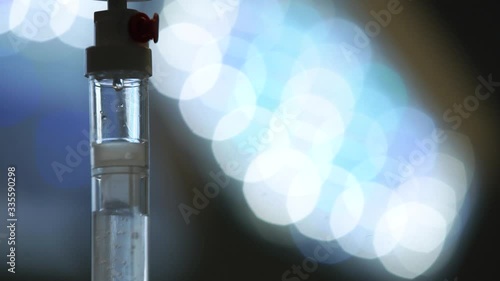 IV (infusion) bags and bottles hanging on poles during a real surgery going on in the background. Patient, illness, treatment, anesthesia, hospital, medicine and healthcare symbolism and concept.