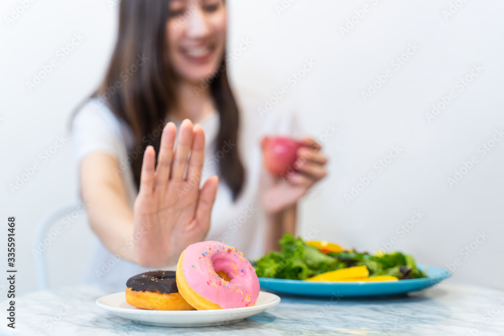 Asian young woman refuse junk food while choose to eat healthy salad and fruit juice for her healthy. Girl take care of herself by having high nutrition food every day. Good food for healthy concept. Asian young woman refuse junk food while choose to eat healthy salad and fruit juice for her healthy. Girl take care of herself by having high nutrition food every day. Good food for healthy concept.