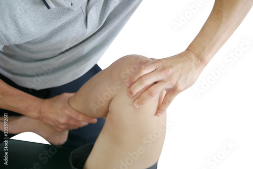 Physical therapist treats knee and leg to the patient on white background