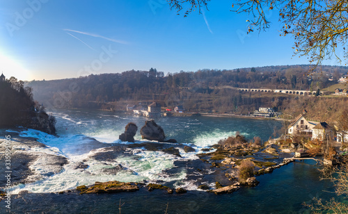 Stunning aerial panorama view of the Rhine Falls, the most powerful waterfall in Europe on the High Rhine river, on sunny autumn day with blue sky cloud in background, Schaffhausen, Switzerland