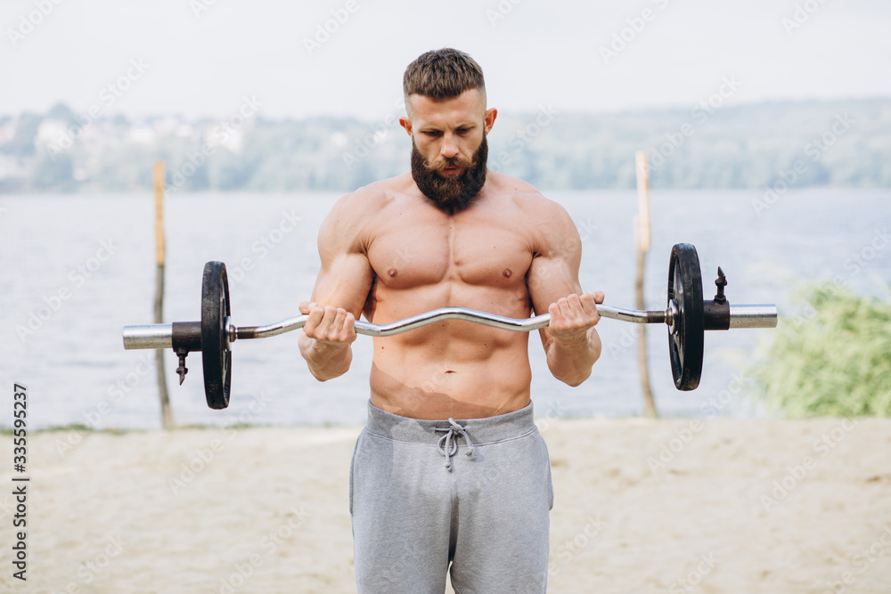 Muscular and bearded mustachioed man doing exercises with barbell outdoors. Bodybuilding and outdoor sports concept
