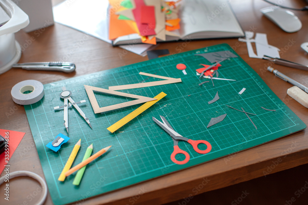 Fototapeta premium Workplace for paper craft. Progress with paper art, cutting on green cutting mat.