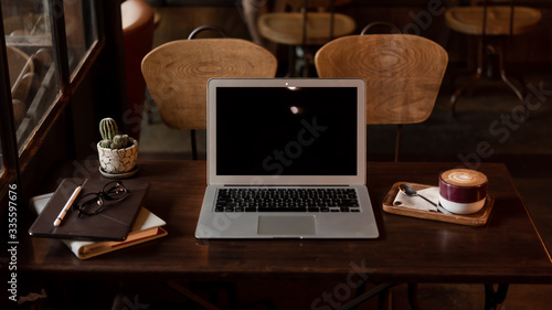 Laptop on wooden table with tablet and organizer in the morning in a cafe