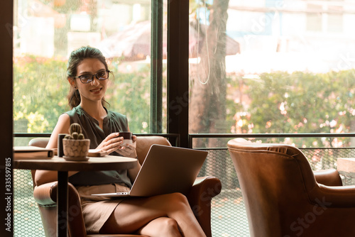 Beautiful caucacsian woman wear glasses use internet via laptop in cafe during morning and have a cup of coffee