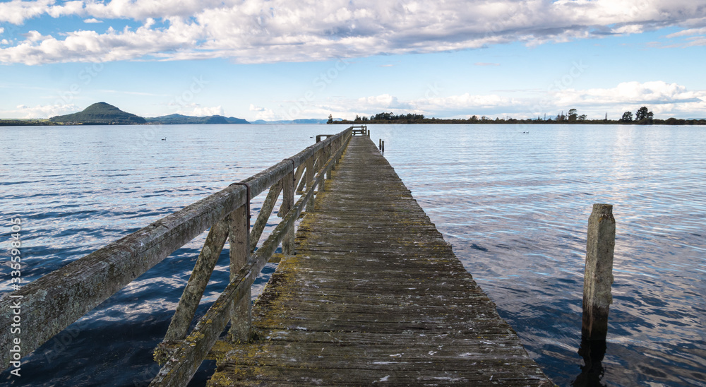 Fototapeta premium Old wooden wharf centered shot during sunset. Location is Tokaanu Wharf locate in Taupo region of North Island, New Zealand.