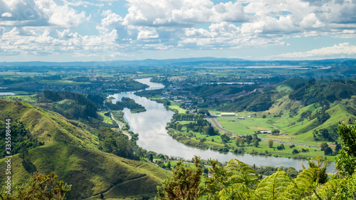 Panoramic view on river valley with lush green and river flowing through the shot during sunny day with blue sky and some clouds. On the picture is Waikato  longest river in New Zealand.
