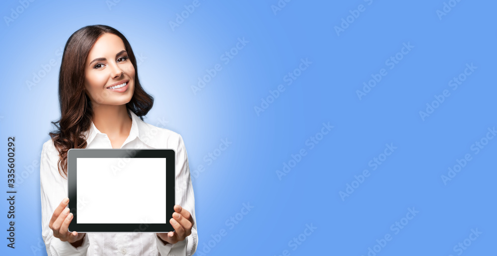 Cheerful beautiful brunette confident businesswoman showing blank no-name tablet pc monitor, over light blue background, with copy space for some text. Success in business concept. Cheerful beautiful brunette confident businesswoman showing blank no-name tablet pc monitor, over light blue background, with copy space for some text. Success in business concept.