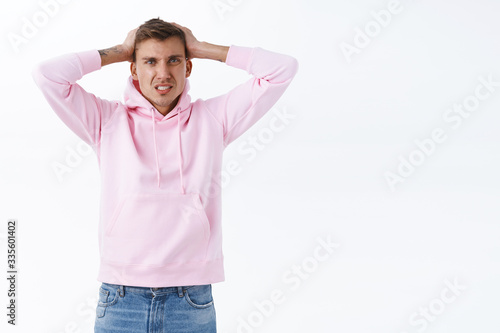 Troubled young frustrated guy got in troubled, dont know what do, shaking head in denial, grimacing disappointed, losing or failing, distressed looking camera, standing white background