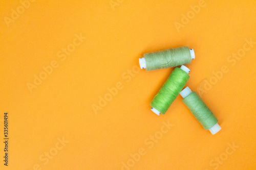 Green spool of thread on a yellow background. The concept of needlework, sewing.