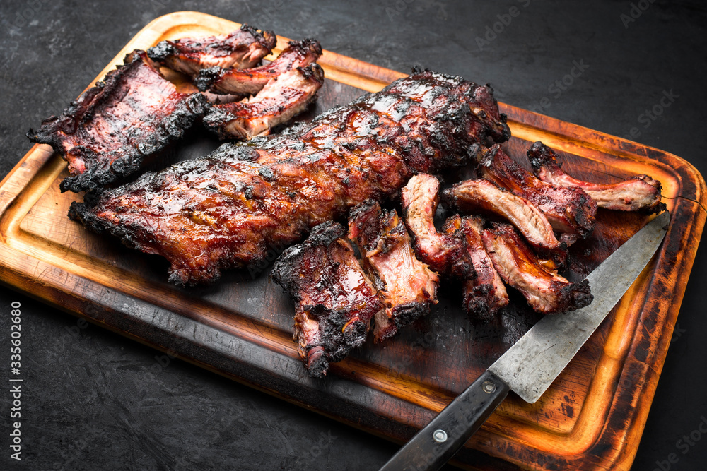 Barbecue pork spare loin ribs St Louis cut with hot honey chili marinade burnt as closeup on a wooden cutting board