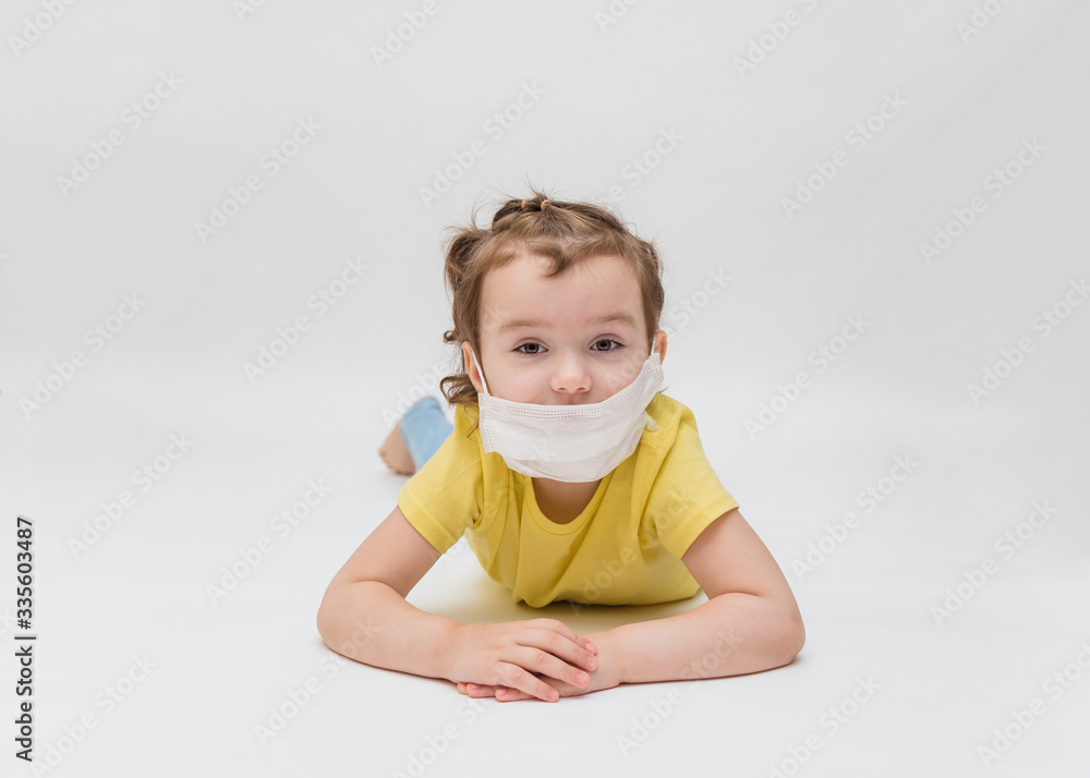 On white background with copy space. A little girl in a mask. Prevention of coronavirus. Stay home On white background with copy space. A little girl in a mask. Prevention of coronavirus. Stay home