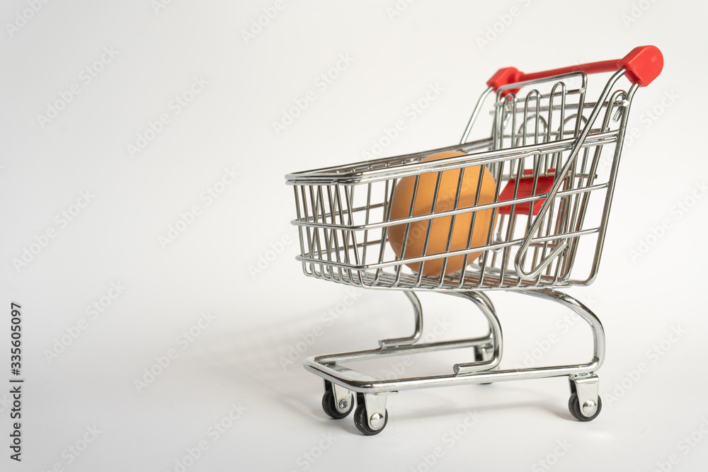 toy little consumer food trolley from steel with red plastic handle on a gray background with one fresh egg inside. empty space toy little consumer food trolley from steel with red plastic handle on a gray background with one fresh egg inside. empty space